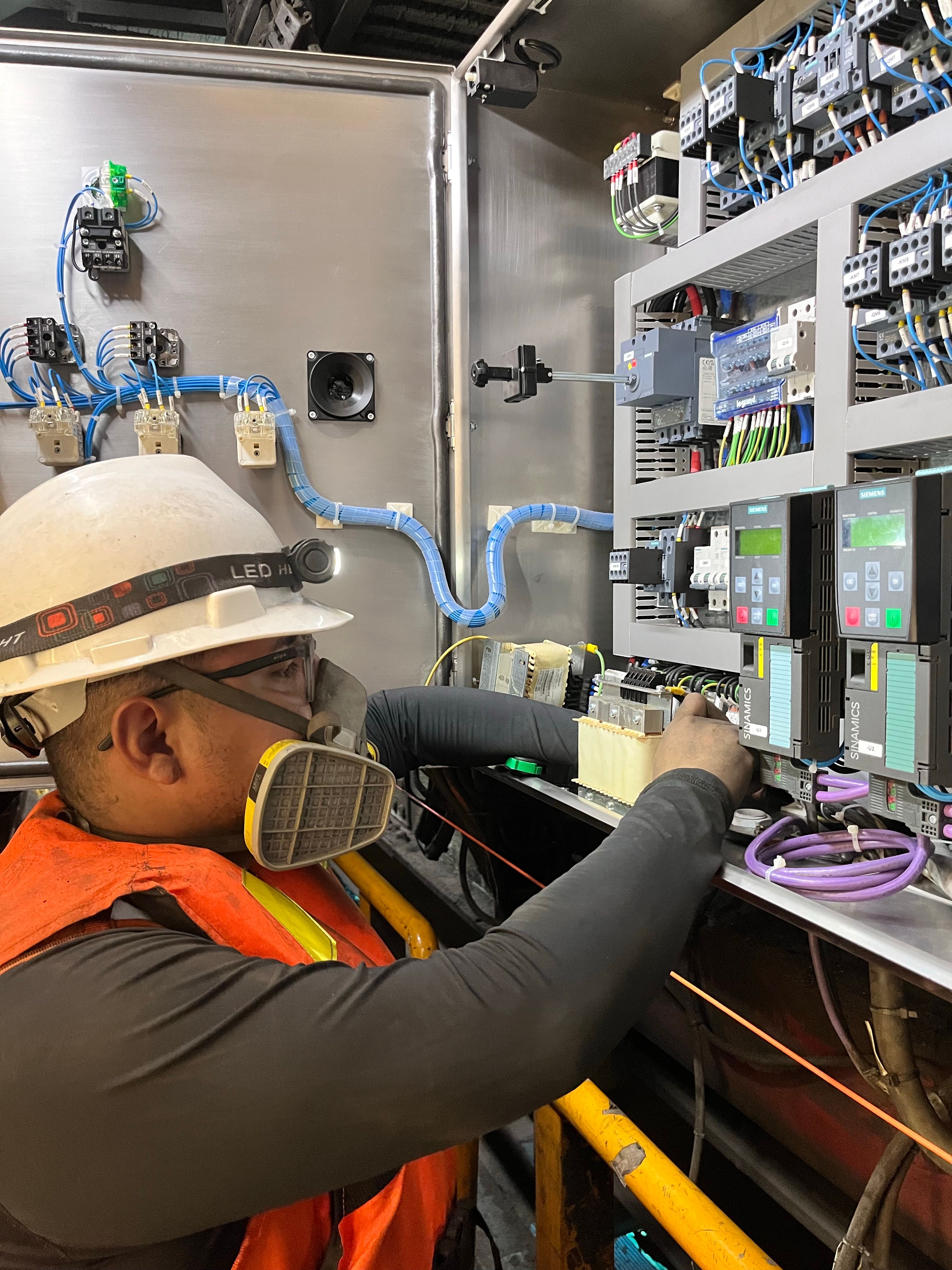Electrician in protective gear working on a commercial control panel