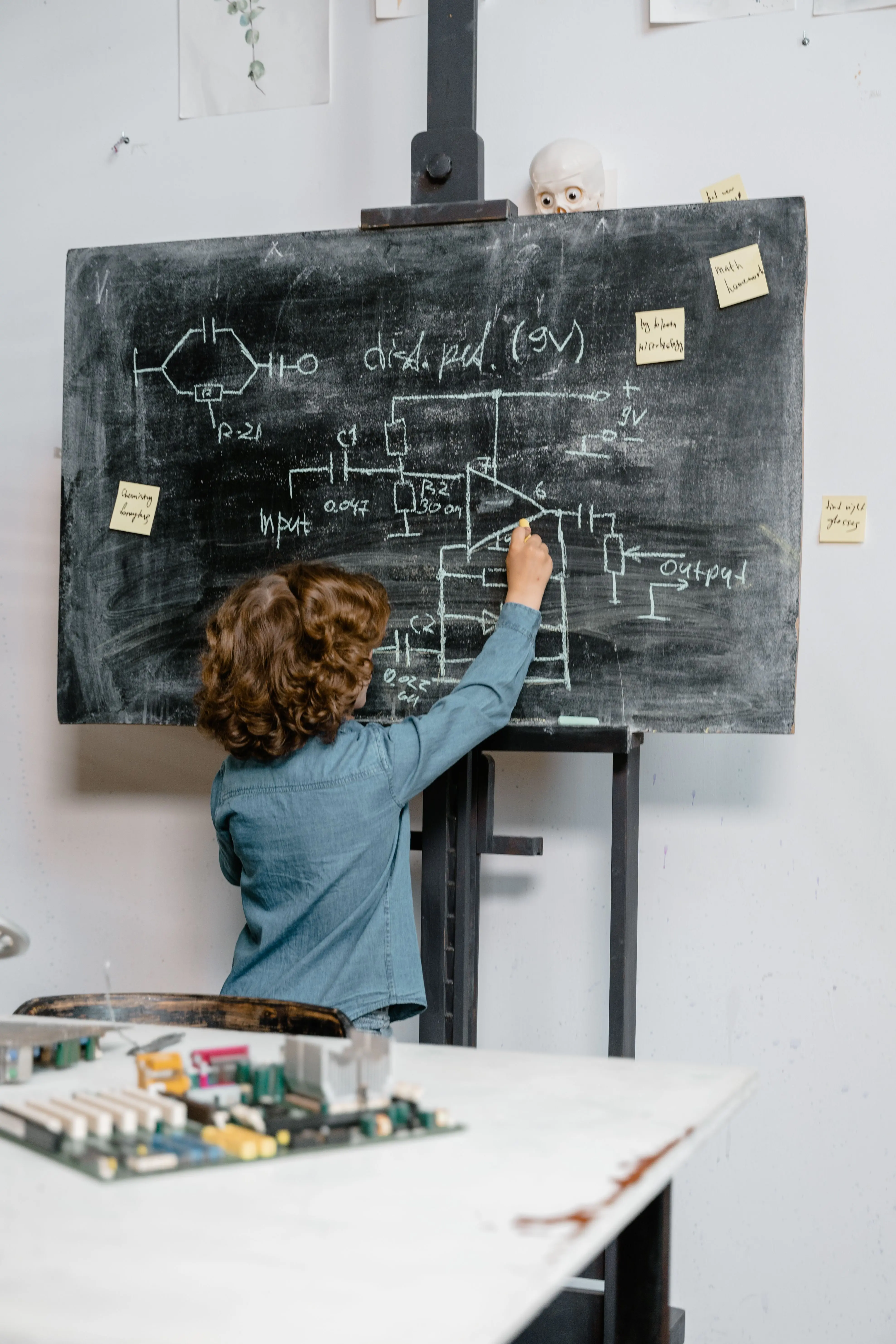 School pupil drawing an electrical circuit on a blackboard